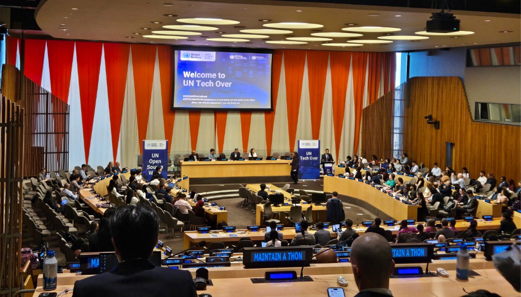 A full auditorium at UN Headquarters during UN Tech Over, the opening day of UN Open Source Week 2026, with Maintain-a-Thon nameplates visible on delegates' desks.
